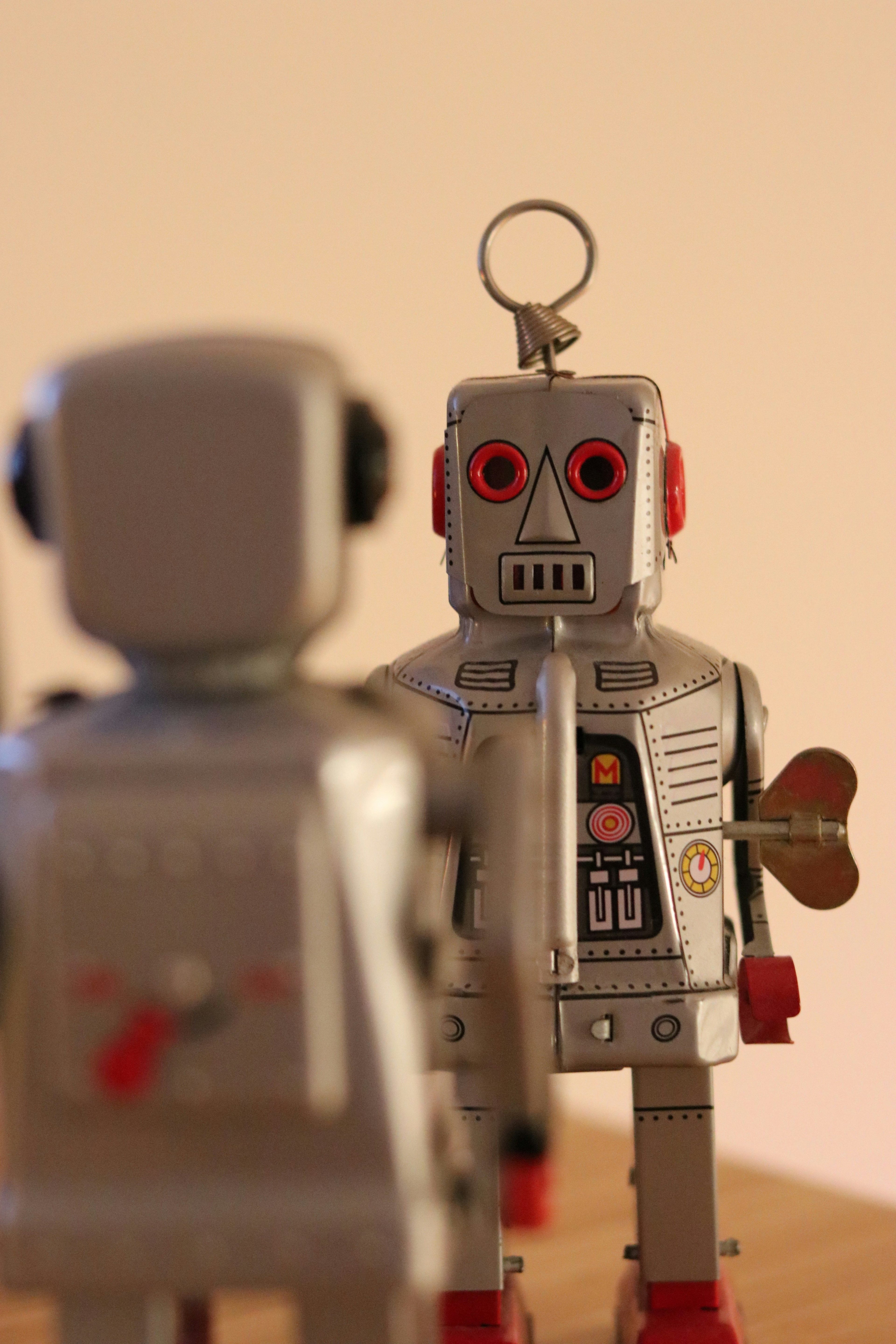 Twee vintage blikken robots staan tegenover elkaar in een gesprekssituatie. De afbeelding symboliseert reflectie op kunstmatige intelligentie — technologie die naar zichzelf kijkt en kritisch bevraagd wordt.